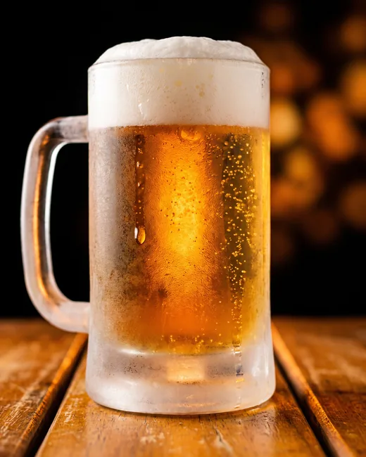 Caneca de chopp gelada com espuma cremosa e condensação no vidro.