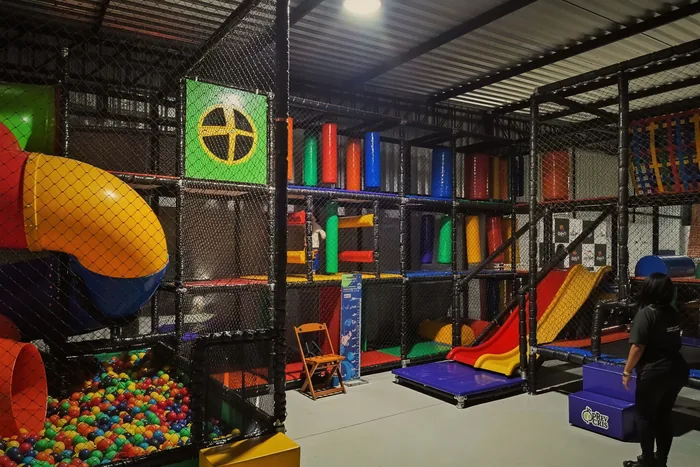 Espaço kids com piscina de bolinhas, escorregadores e circuito de escalada em estrutura de rede.